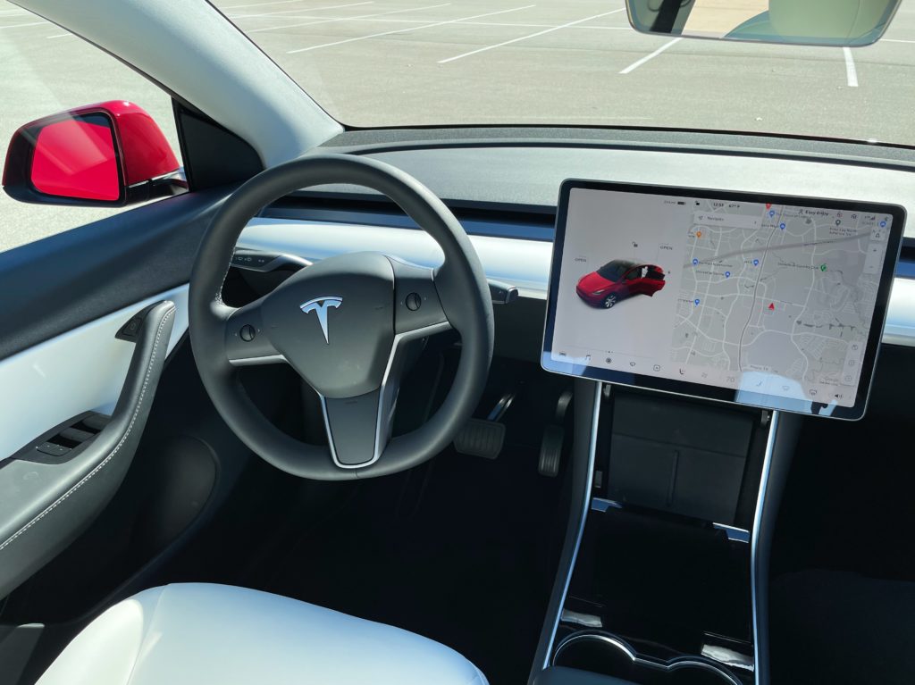showing the Tesla dashboard inside a Model Y, featuring the steering wheel and center console monitor