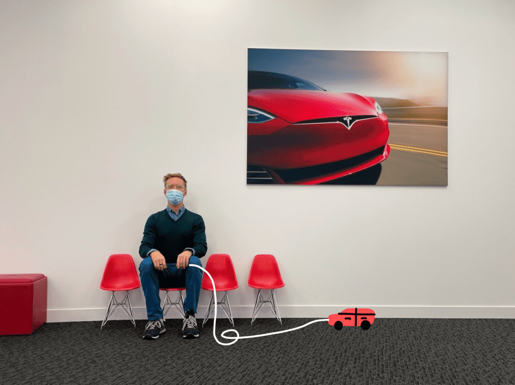 Nick Gray waiting inside lobby of Tesla Service Center in Plano, sitting on small red chairs, cartoon drawing with toy car