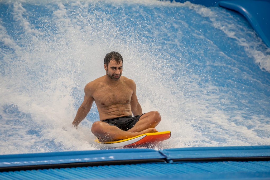 Man sitting on a boogie board, Neville on the Flowrider surf machine in Texas