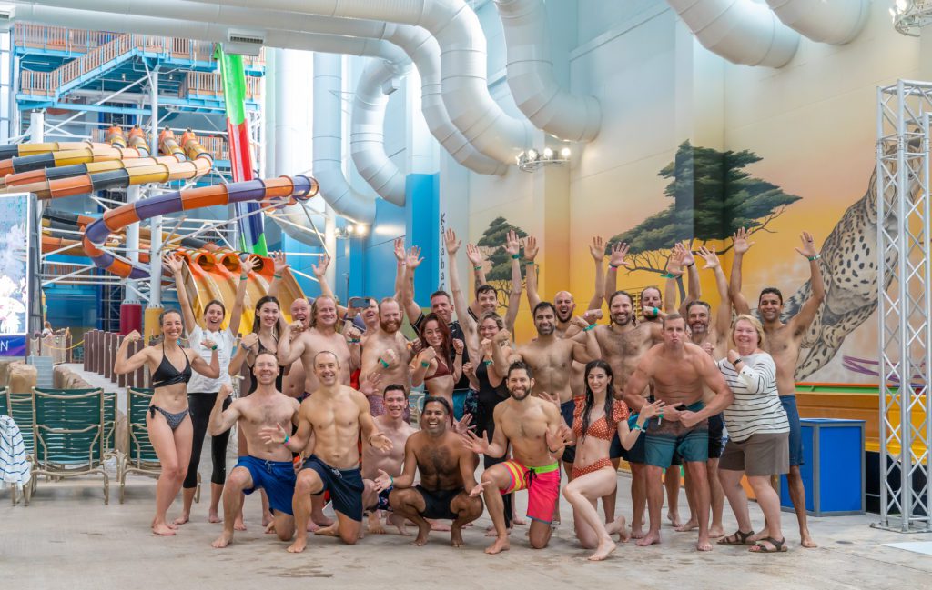 group photo of approximately 35 people standing and kneeling in front of colorful indoor water slides in Round Rock Texas at Kalahari Resorts for Nick Gray's birthday party