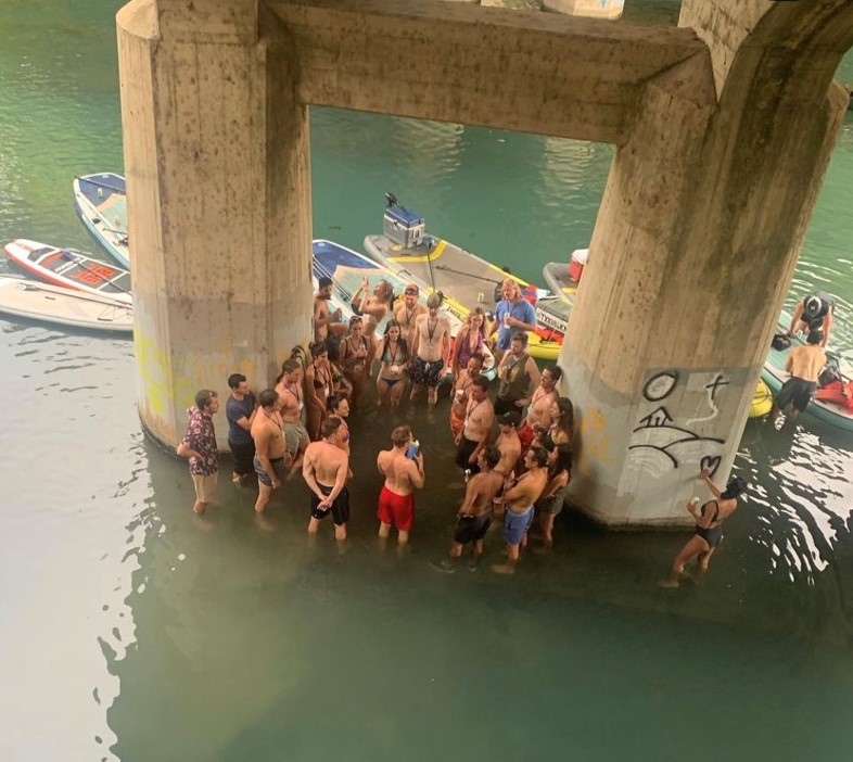 a group of people in a circle under a bridge