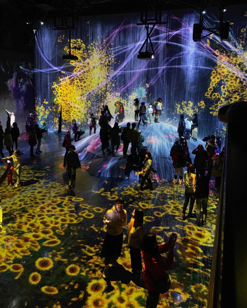 Huge black room with lots of video projections. Showing sunflowers and butterlies.