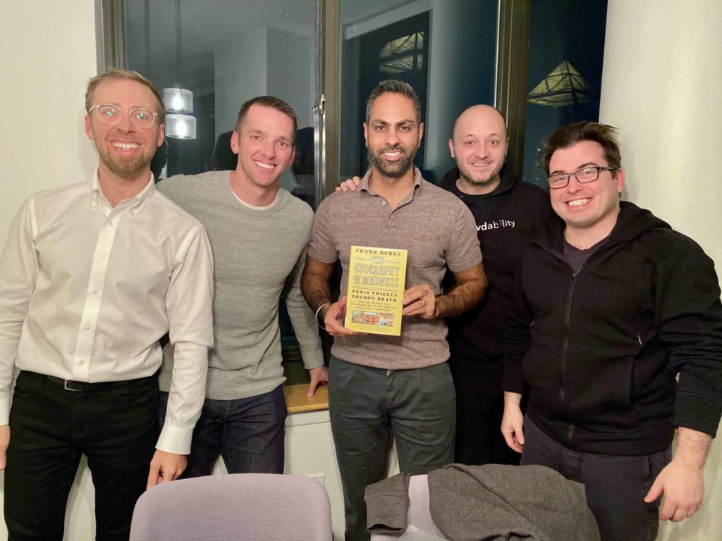 Five guys standing together, one is holding the book in the middle
