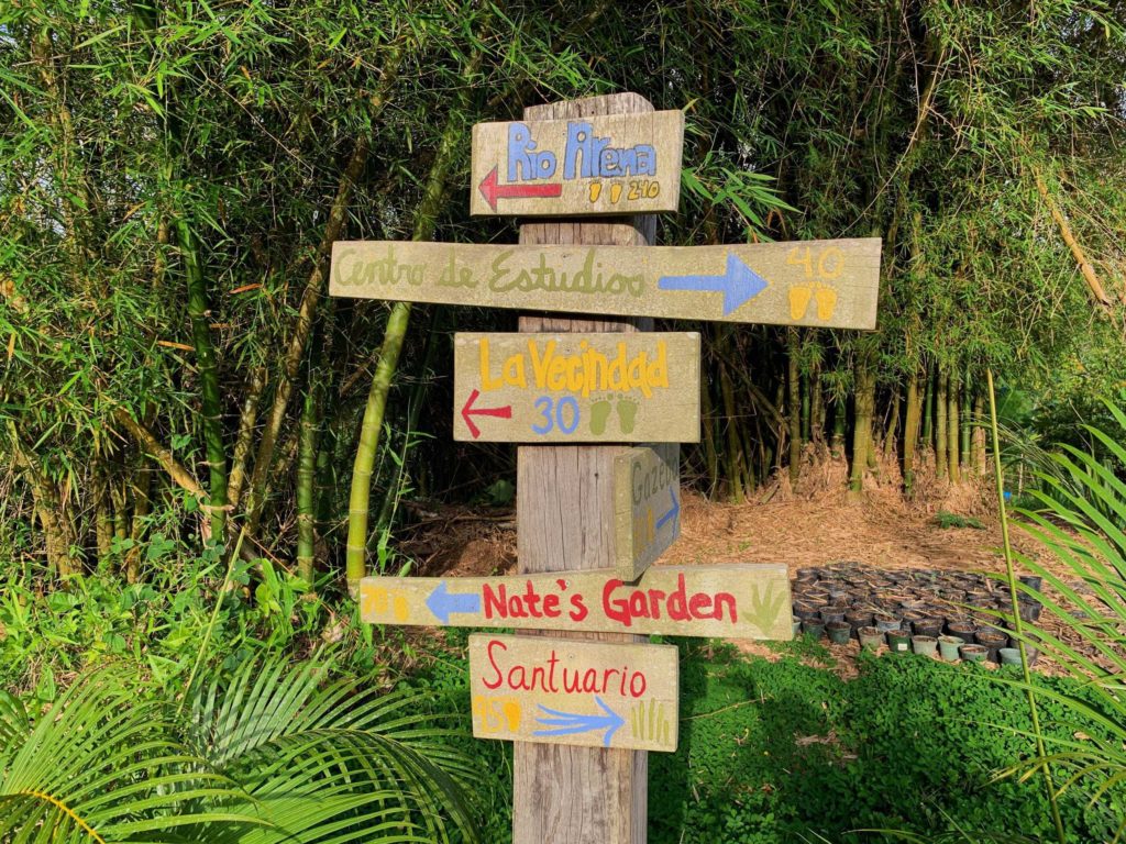 Wooden sign with locations pointing to Rio Arena, Centro de Estudio, La Vecindad, Nate's Garden, and more