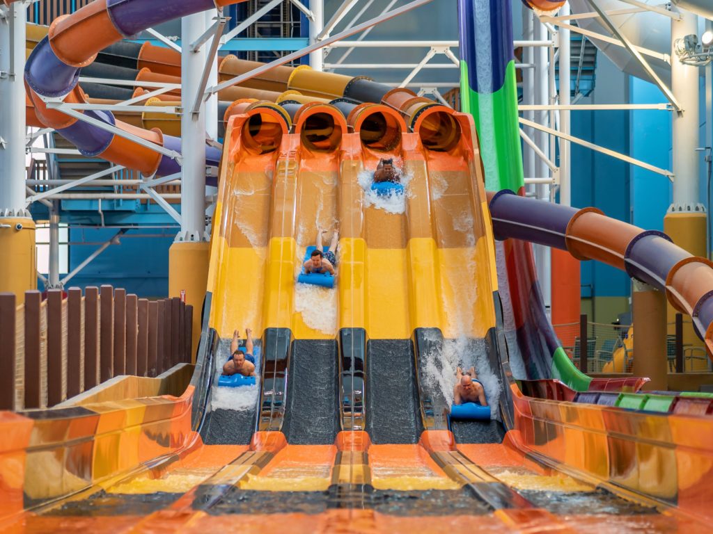 four men racing down an indoor water slide race