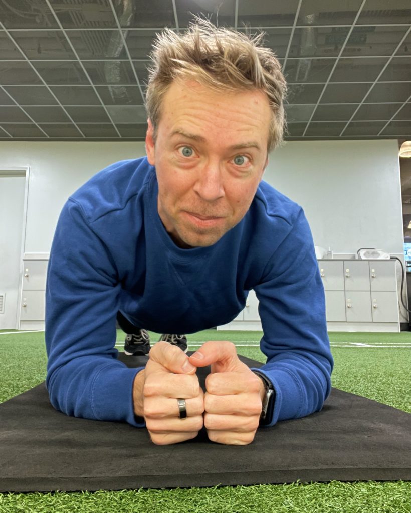 Attractive man, blonde hair, blue eyes, looking into camera as he does a plank (Nick Gray)