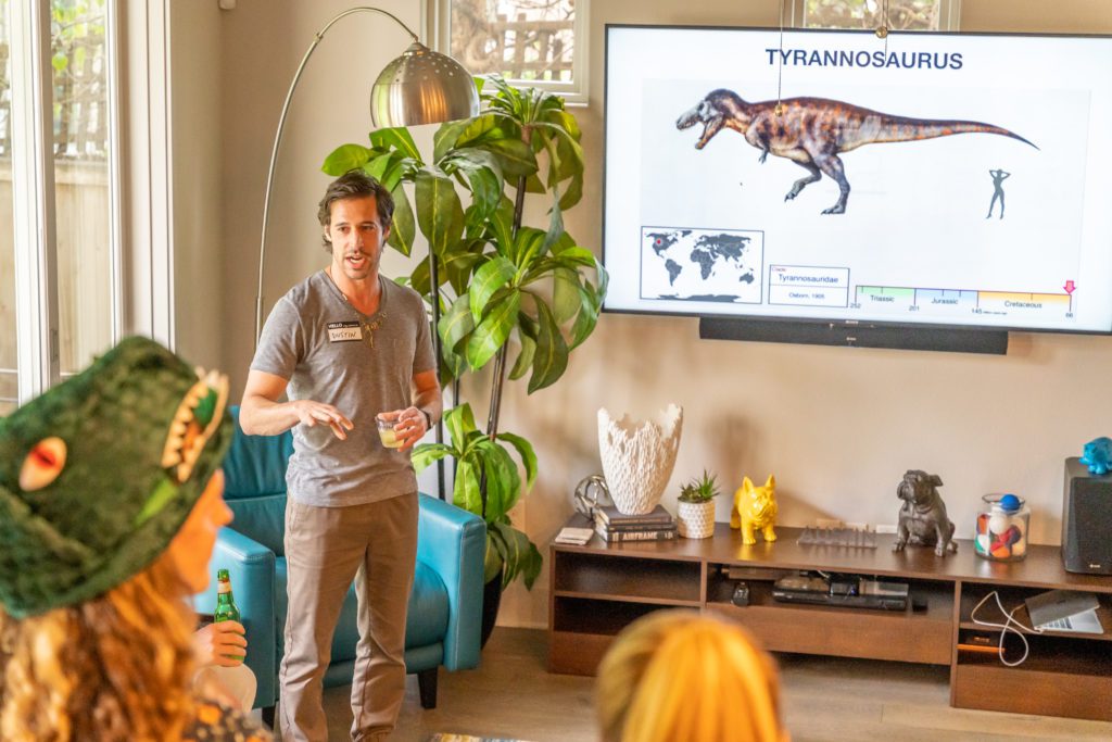 Dustin Growick standing in front of a TV with a T-Rex on it