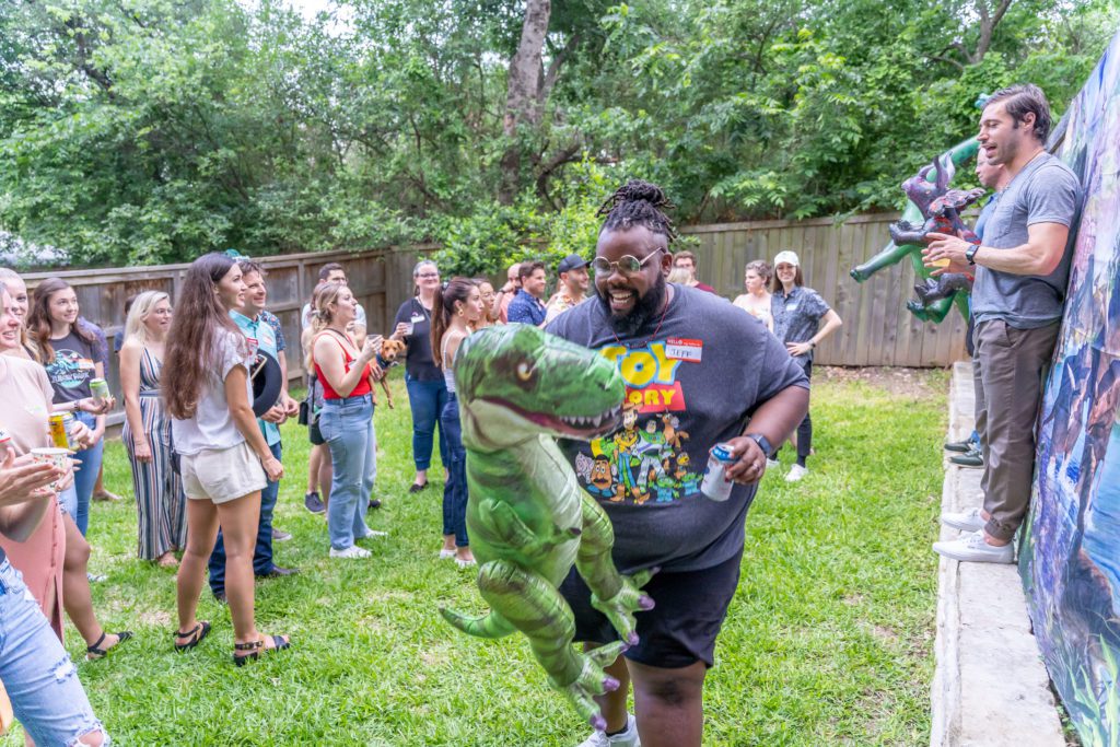 Man holding an inflatable T-Rex prize at a dinosaur party for adults