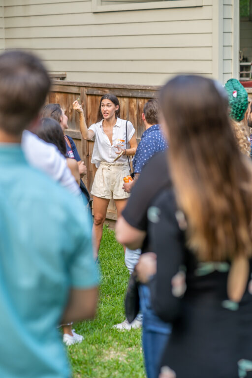 woman dressed like she's on a safari showing off a tiny dinosaur toy at a party