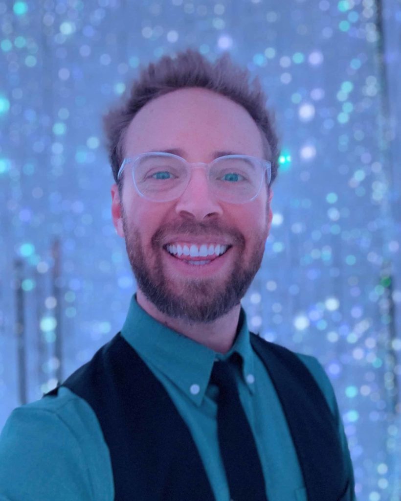 Man's selfie inside, wearing a black vest and tie (the man is me)