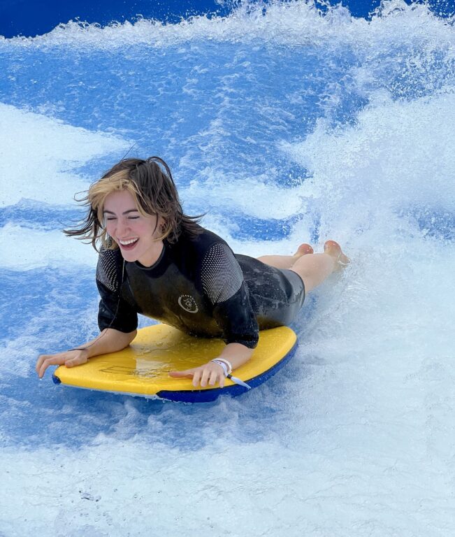 woman wearing a wetsuit riding the Flowrider machine