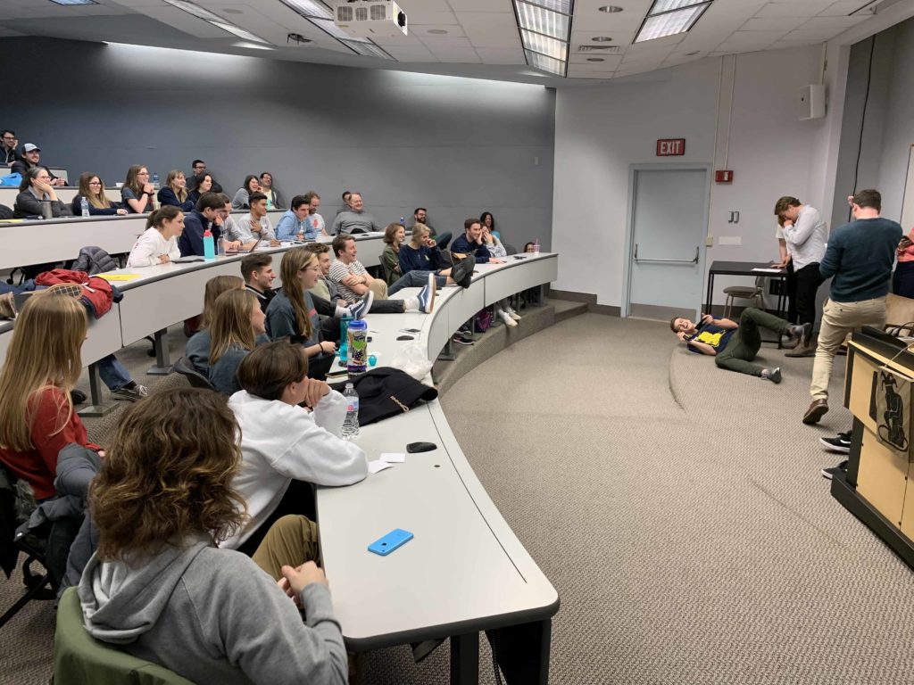 Comedy troupe members watching people present on stage at Wake Forest University