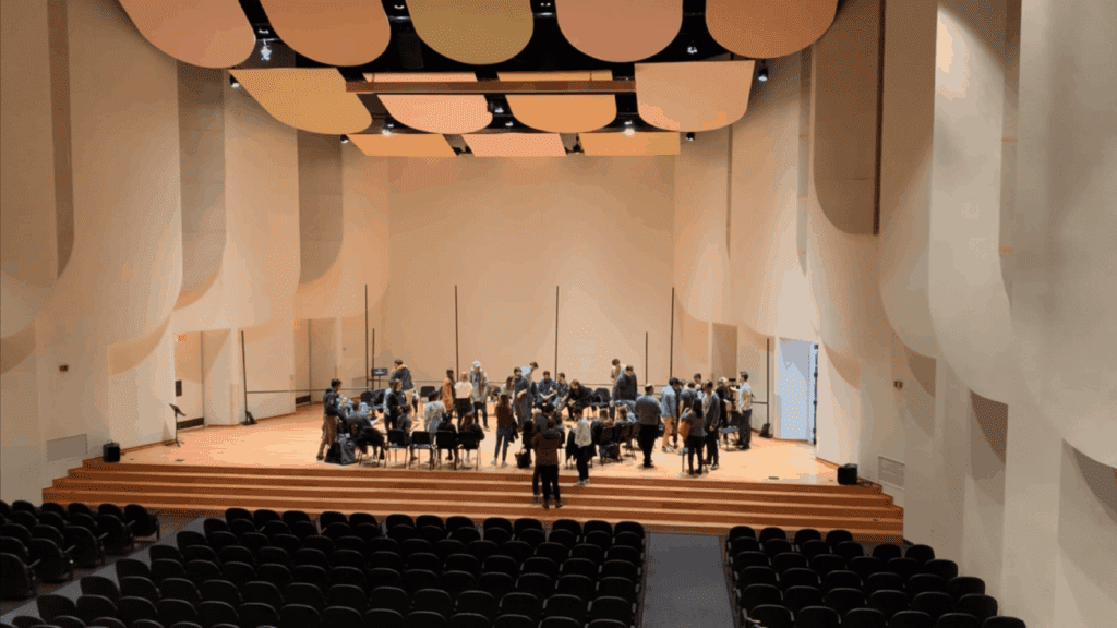 Large recital hall on the campus of Wake Forest University. Black chairs and people on stage
