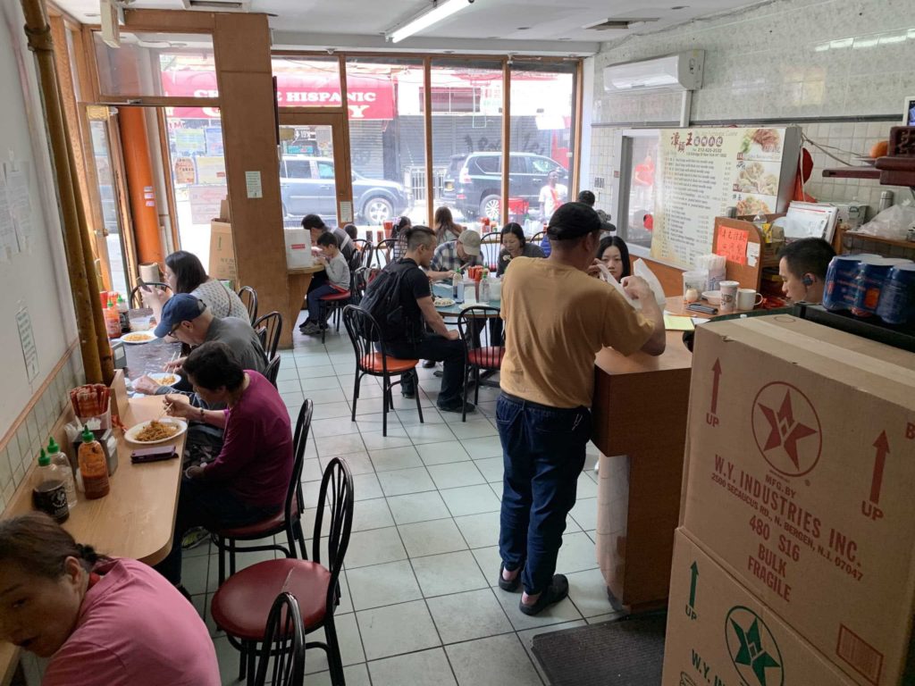 Interior of a Chinese restaurant in New York City: people sitting down, and a counter on the right side