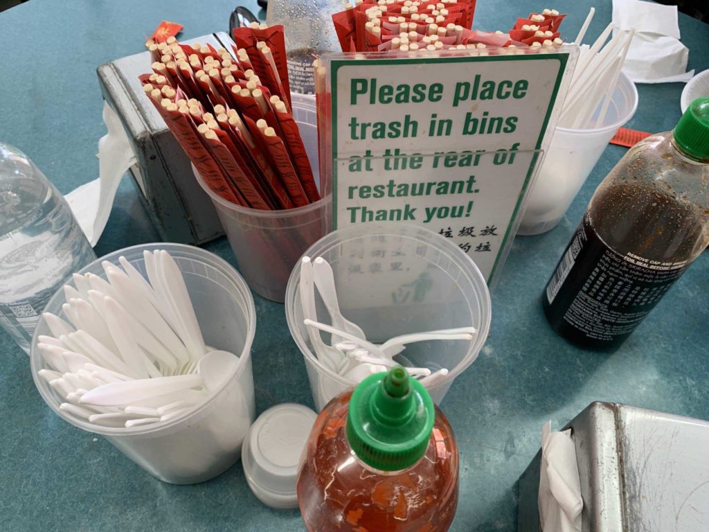 Sign says "Please place trash in bins at the rear of the restaurant. Thank you"