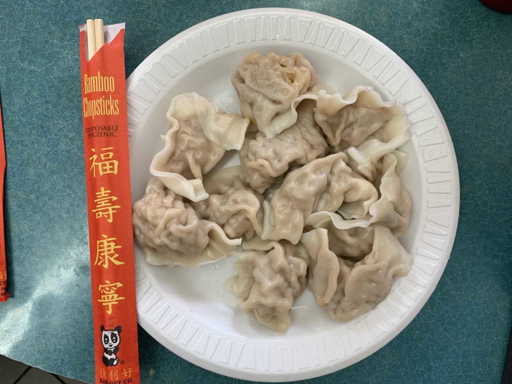 White styrofoam plate, chopsticks on left, and 10 dumplings on plate