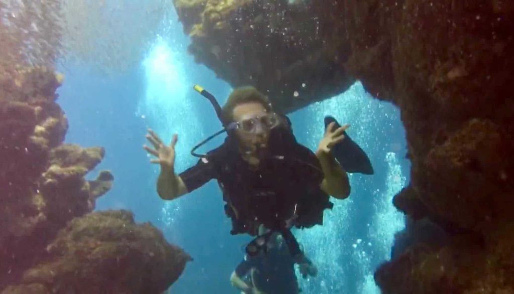My hands are up, I’m wearing a full SCUBA mask, underwater