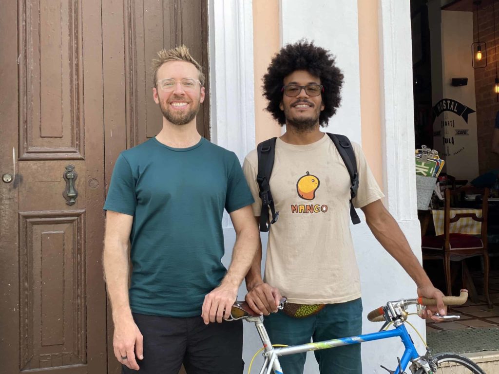 Two men standing and smiling for the camera with a bicycle