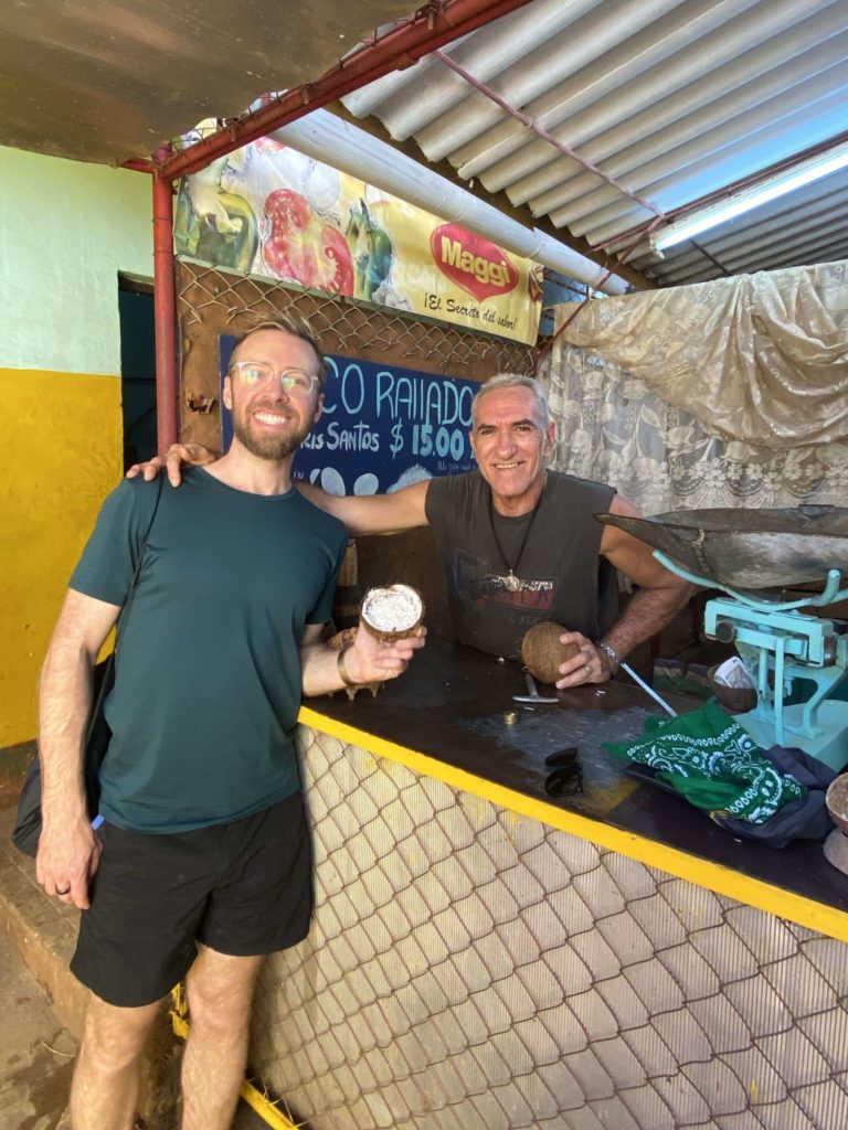 Two men posting for the camera, both holding coconuts