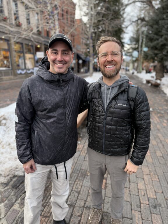two men smiling wearing black jackets