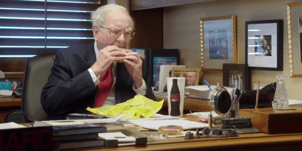 Warren sitting at his desk in the documentary, eating a McDonalds burger