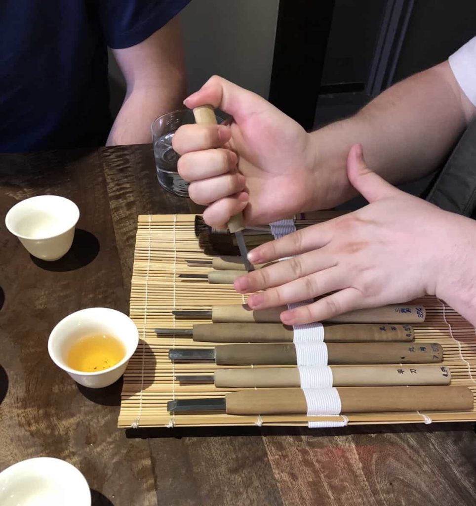 Person's hands holding a series of tools in a bamboo wrapper