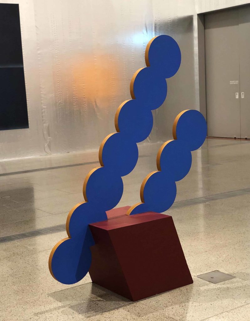 Sculpture with purple dots and a wooden base