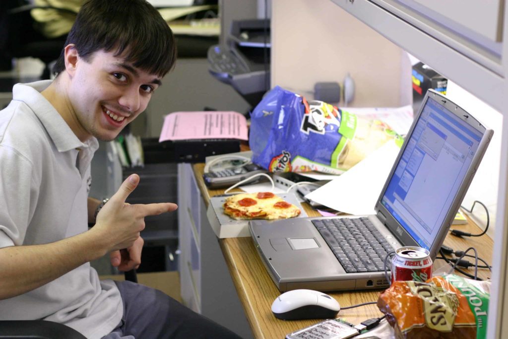 Man with laptop and lots of snacks, pointing at laptop