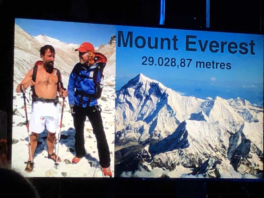 Two men, one without a shirt, another without an arm, near Everest.