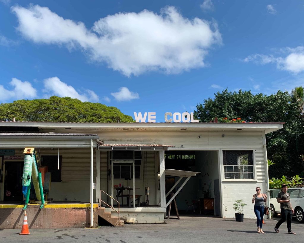 Industrial-looking building with sign on the top that says “WE COOL”