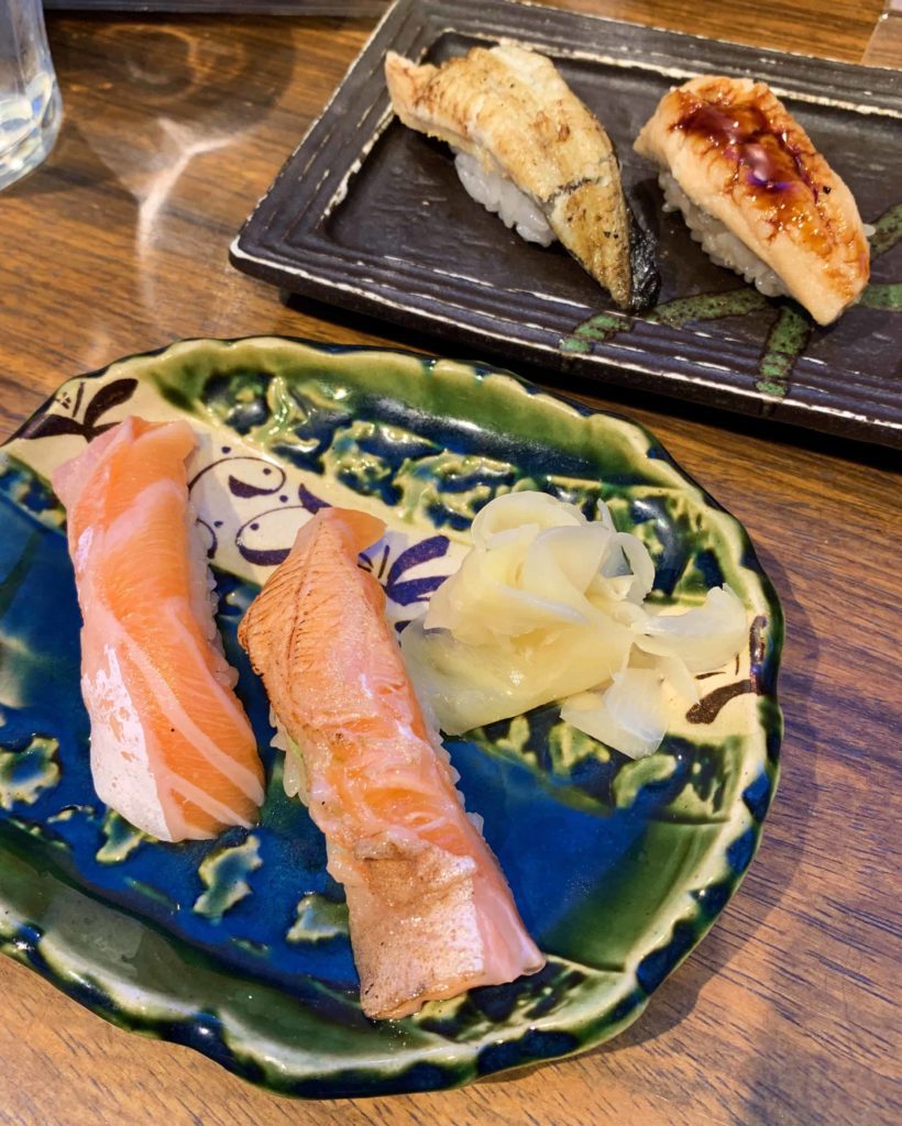 Four pieces of sushi on plates with ginger