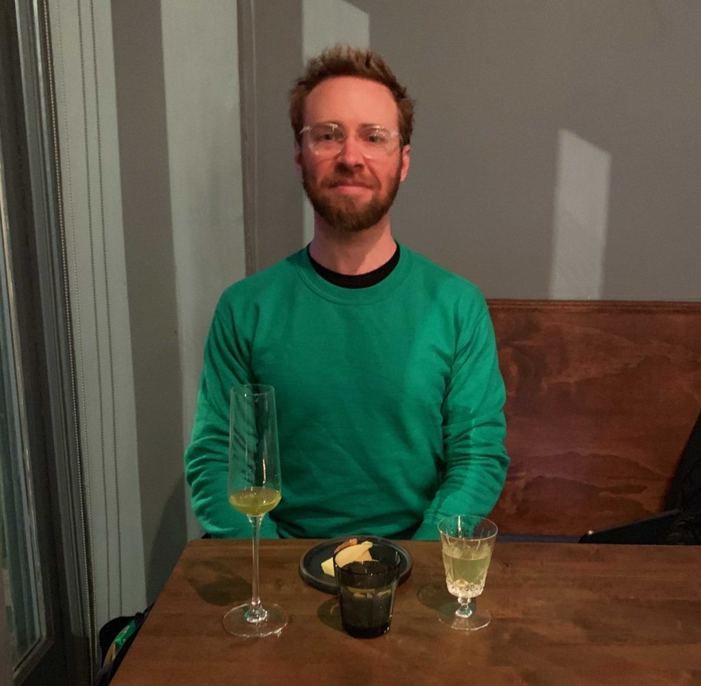 Man wearing a green sweater (me) sitting in front of tea and glasses with tea in them