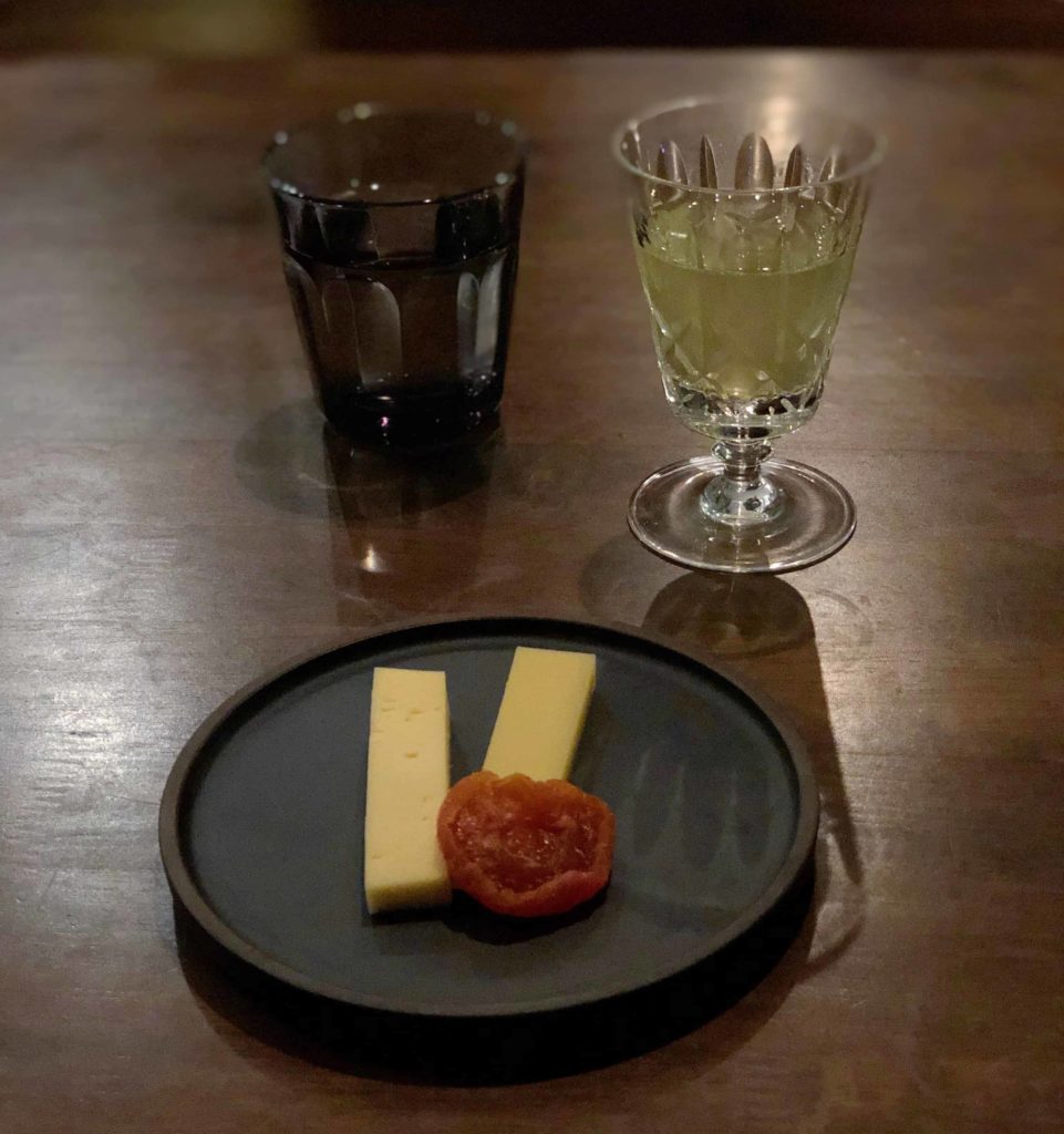 Black plate with two slices of cheese, and a gyokuro sake cup in top right
