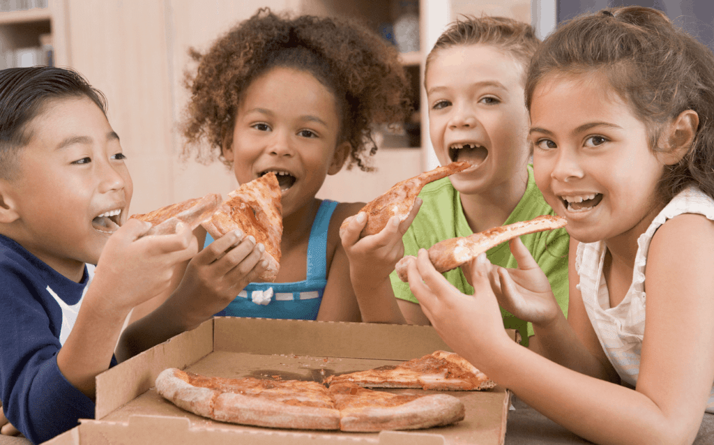 Four kids eating pizza, looking happy