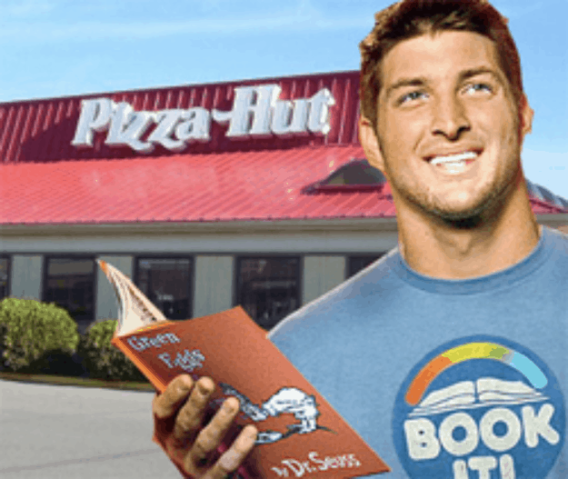 American football player reading book in front of Pizza Hut restaurant