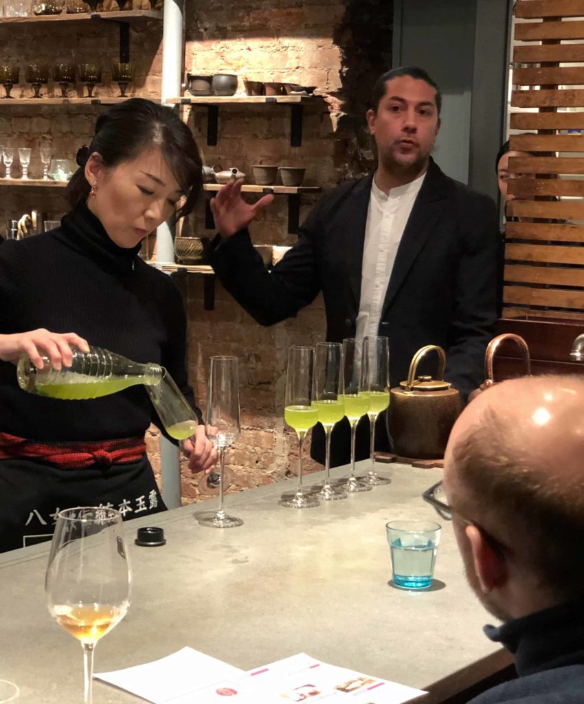 Woman pouring into small glasses and man on right (Stefen Ramirez) explains at 29B Teahouse in New York
