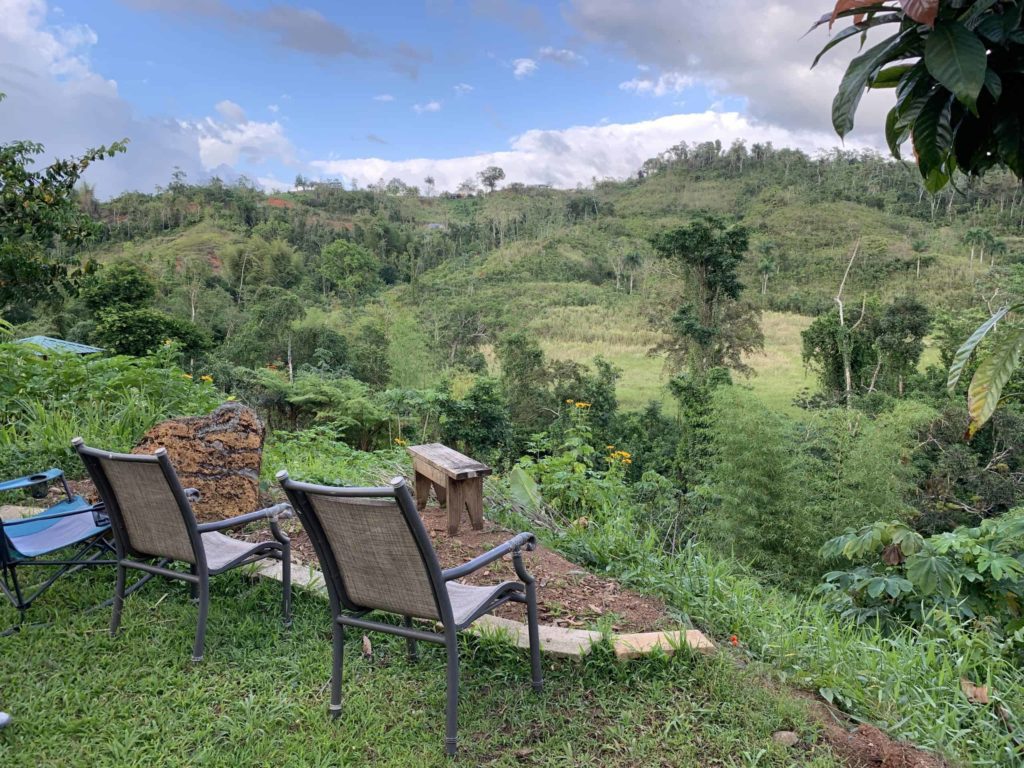 Three chairs and a wooden bench, looking out over green fields