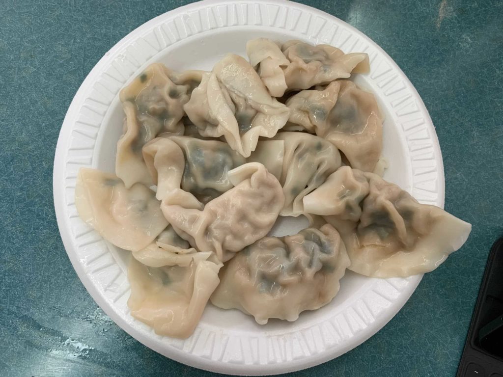 10 dumplings on a styrofoam plate on top of a blue-green table