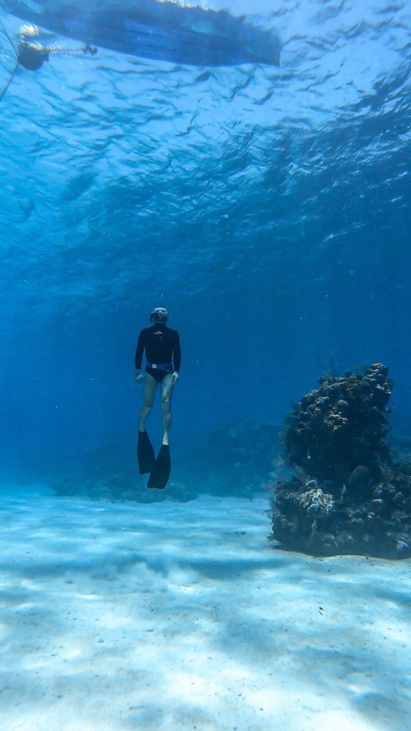 Roatan, Honduras - Man freediving in the ocean, wearing flippers underwater