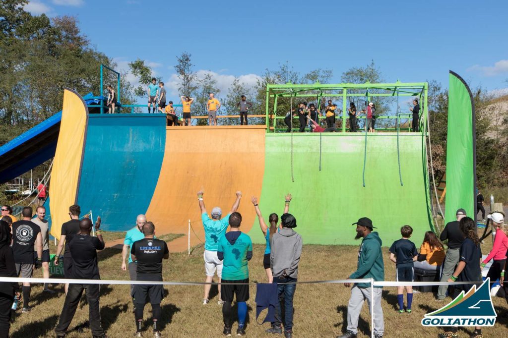 Wooden structure with blue, orange, and green colors - green far right side has four ropes hanging down so people could climb up