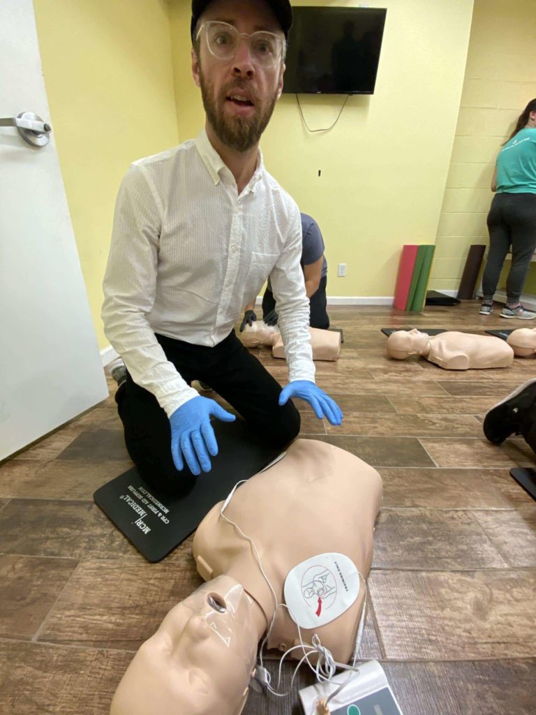 Man performing CPR on a test dummy at Red Cross first aid and CPR workshop in NYC