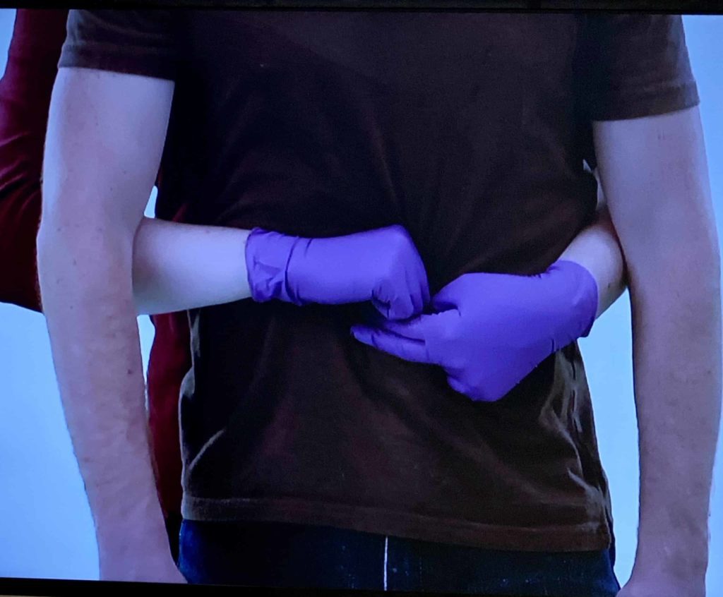 Hands with gloves above bellybutton