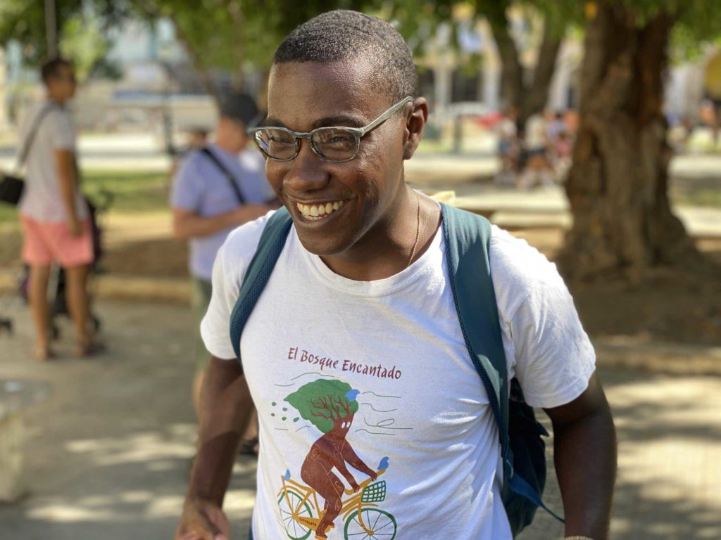 Man wearing glasses and laughing wearing a shirt that says El Bosque Encantado