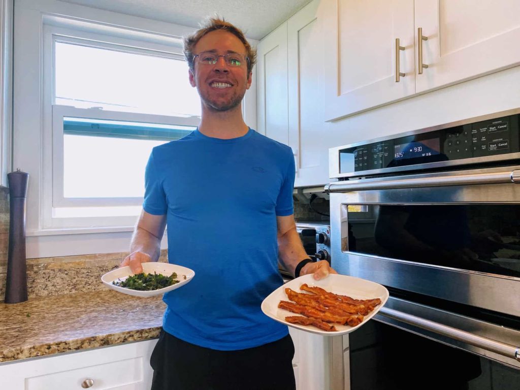 Man wearing blue shirt holding pans from oven