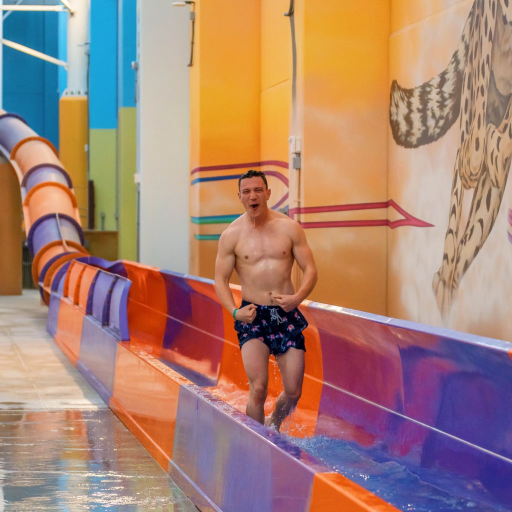 very strong, muscular man walking out of a water slide at Kalahari Resorts
