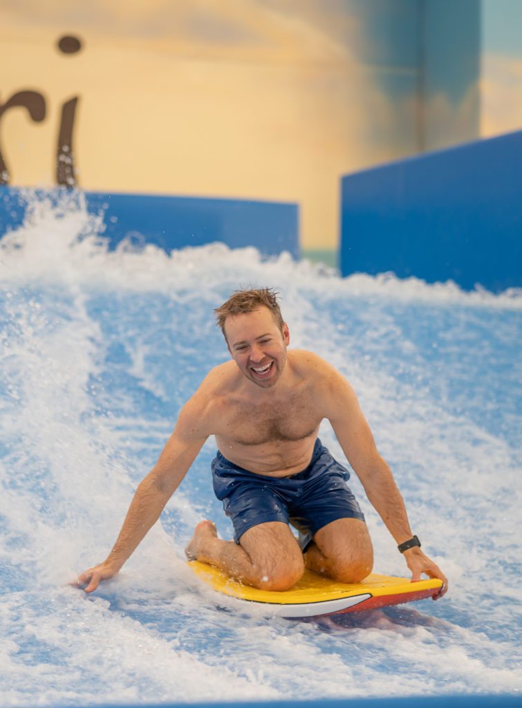 happy man on the Flowrider surf machine knee board boogie board