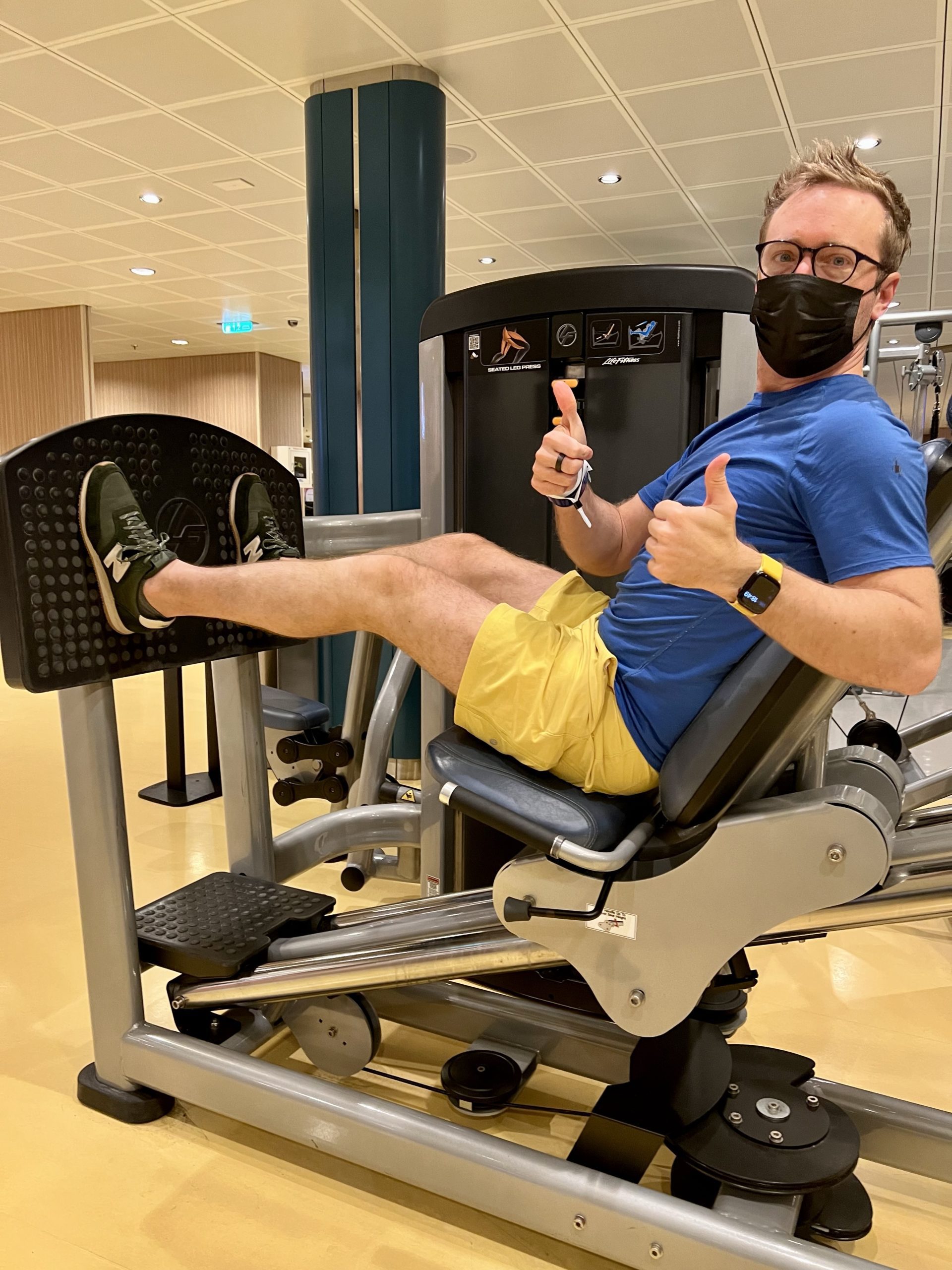 inside the gym, man sitting on leg press weights machine on Symphony of the Seas