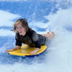 woman wearing a wetsuit riding the Flowrider machine