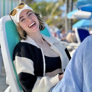 woman wearing hat and sunglasses in a beach chair