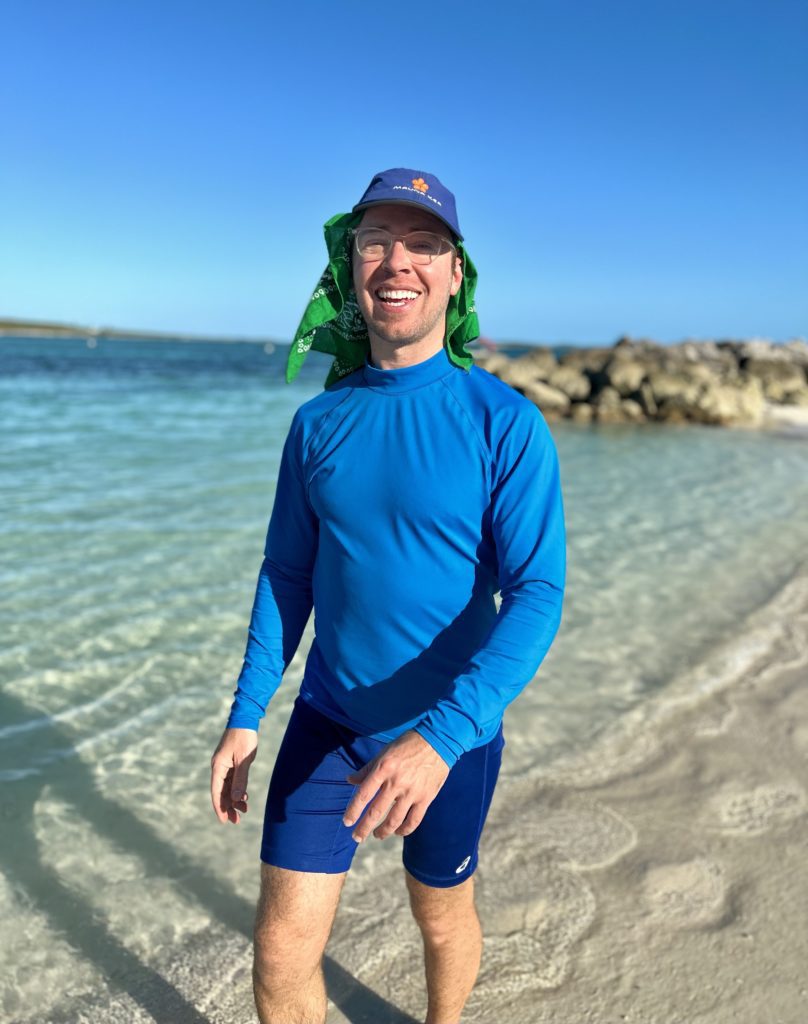 man wearing all blue on the beach in Bahamas with blue rash guard and blue hat